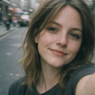 A close street selfie of a woman, face only, no body in frame