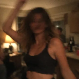A dim, blurry snapshot of a woman dancing at a night party