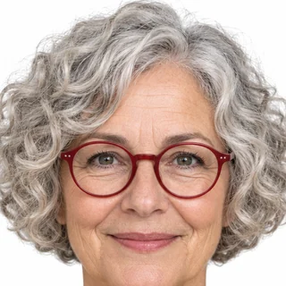 Front-facing portrait on white of a woman with a silver curly bob and red glasses