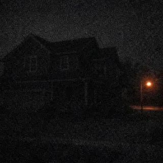 Dark, grainy night photo where the house is barely visible