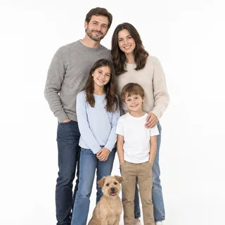 A family of four and a small terrier standing close together on a white background, every face visible
