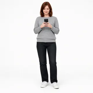 Full-length photo of a woman holding her phone at chest height on a white background