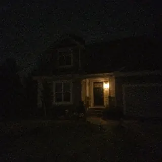 A dark, noisy night photo of a house