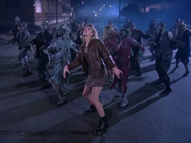 The lead leans sideways with clawed hands held low, zombies in torn clothes doing the same behind her