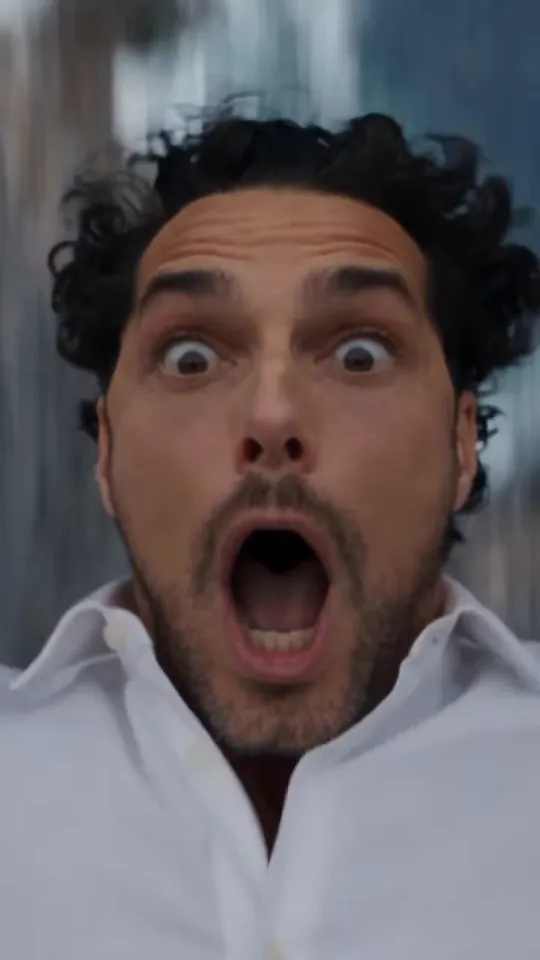 Close-up of the man in mid-air, eyes wide and mouth open in shock, his hair blown upward