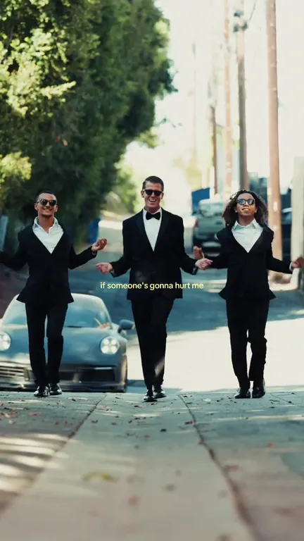 The three dancers holding hands in a line, bouncing toward the camera