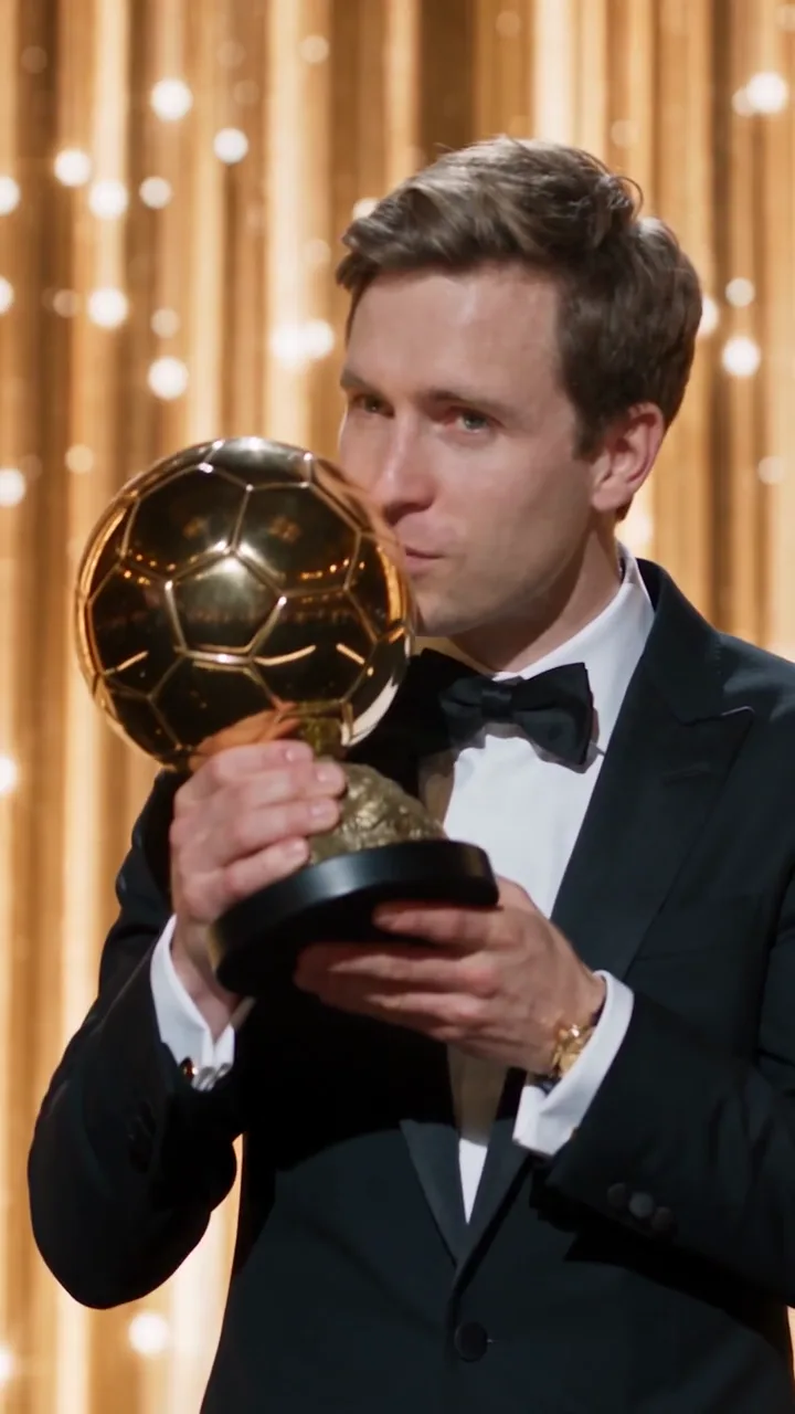 The winner lifts a golden ball trophy on stage while the crowd around the stage applauds