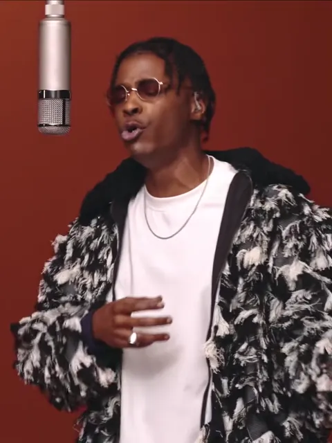 The template's singer in a fringed jacket and white T-shirt under the hanging silver mic