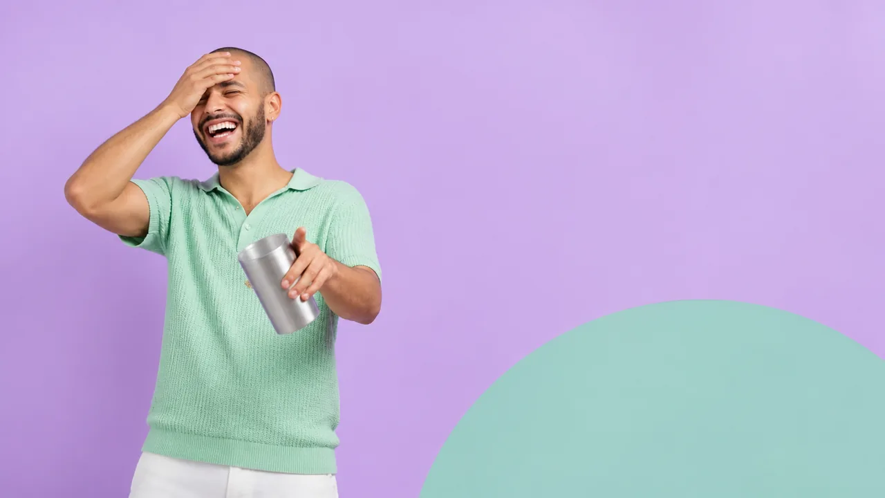 A young man in a mint knit polo laughs with a hand on his forehead and points at the camera in front of a lilac backdrop
