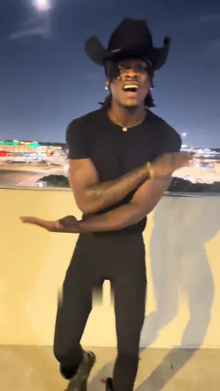 Singer crossing his arms into an X in front of him on the rooftop