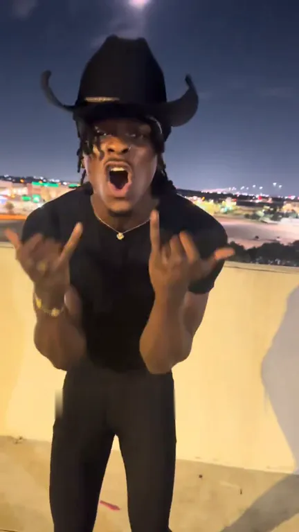 Close-up of the singer screaming with both hands raised in hand signs in front of the camera