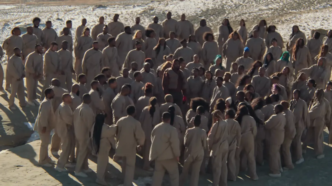 A wide view of the hillside choir, dozens of singers filling the frame around the still figure