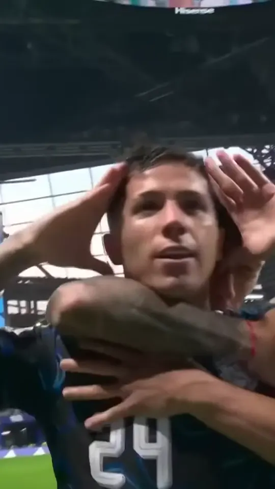 A teammate hugs the scorer from behind while the scorer keeps both hands at the ears