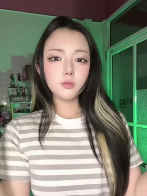 A woman with long dark hair in a striped tee faces the camera before the cut