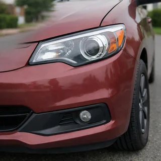 Close-up of a red car's headlight and bumper, the rest of the car cut off