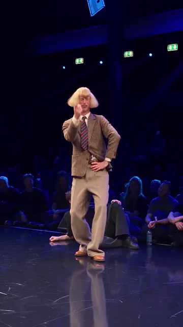 Dancer standing with one hand on his hip and the other at his chin