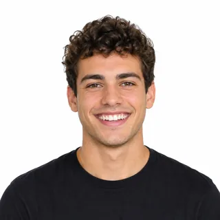 A young man with short curly hair grinning straight at the camera on a white background