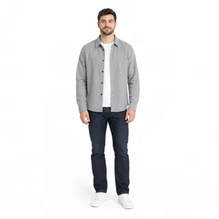 A young man with a trimmed beard in a grey overshirt and dark jeans, standing full length on a white background