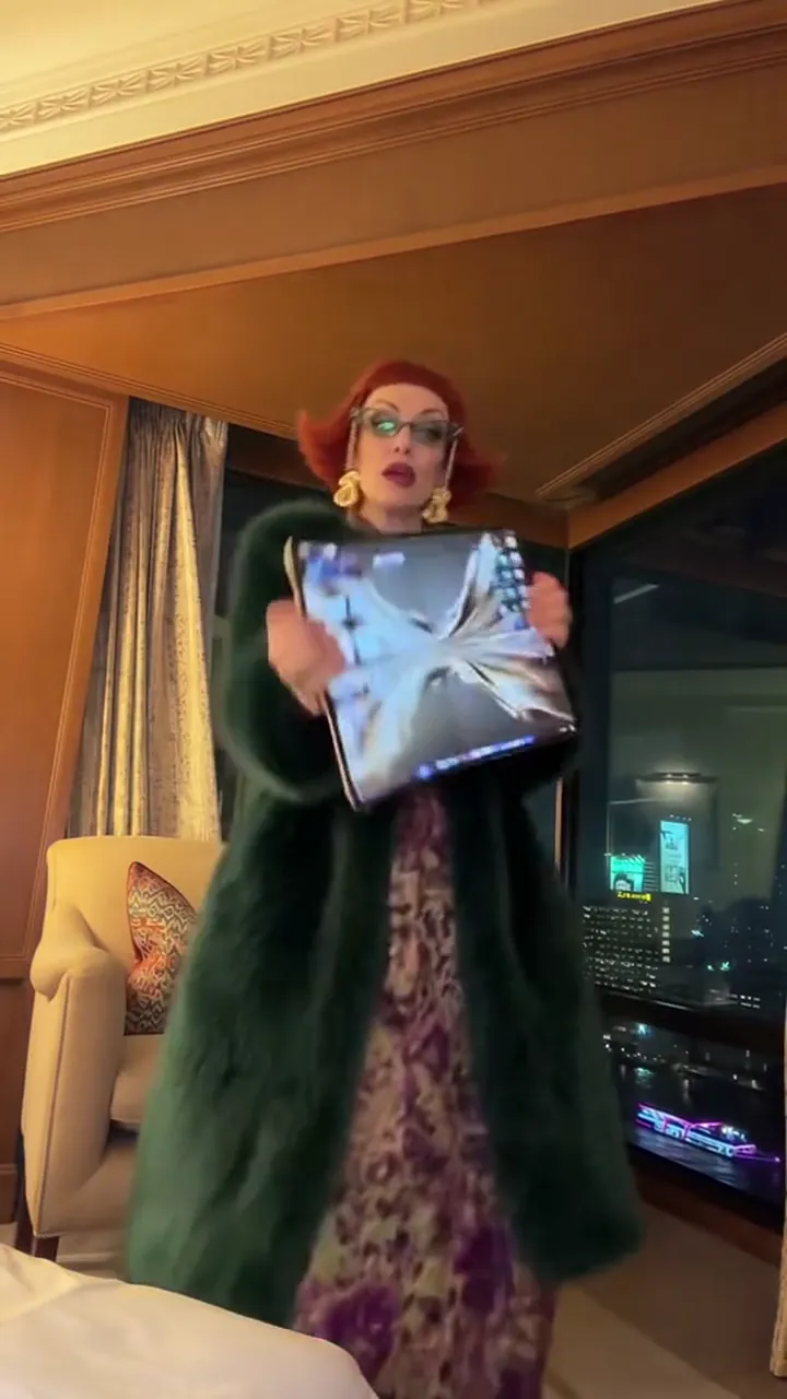 A figure dancing in the middle of a hotel room, lamps and curtains behind them