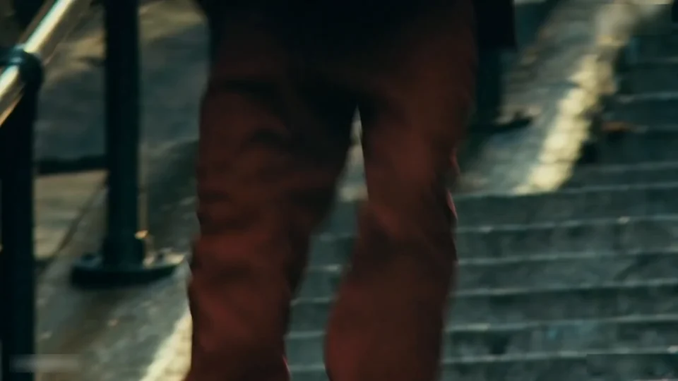 A close-up of the dancer's legs and shoes stepping down the concrete steps