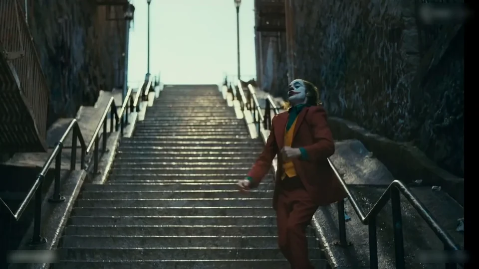 The dancer mid-hop on one leg on the staircase, the other knee lifted