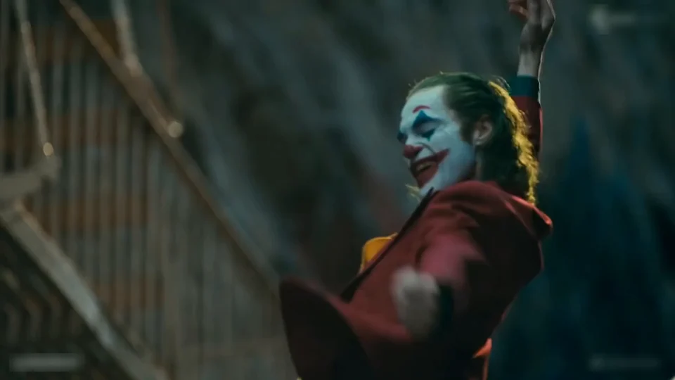 A close-up of the dancer laughing with one hand raised near the face on the staircase