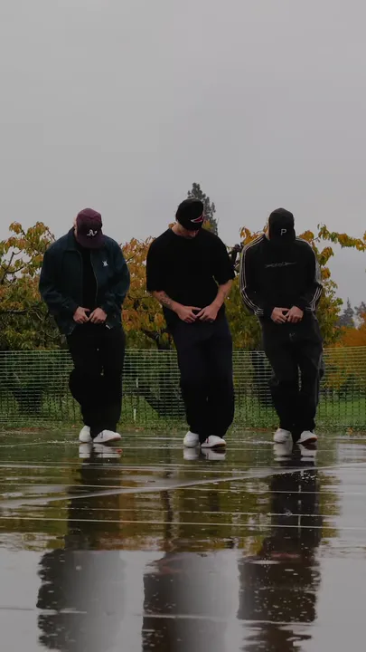 Three dancers in a line on the wet court, heads bowed, hands at the waist.