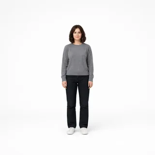 Full-length photo of a woman in a grey sweater and jeans standing on a white background