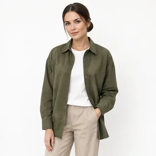 Woman in a plain olive overshirt and beige trousers on a white background