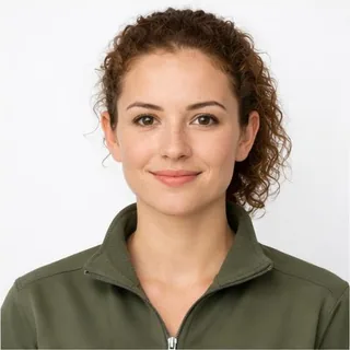 A woman with curly auburn hair photographed in soft, even light against a white background