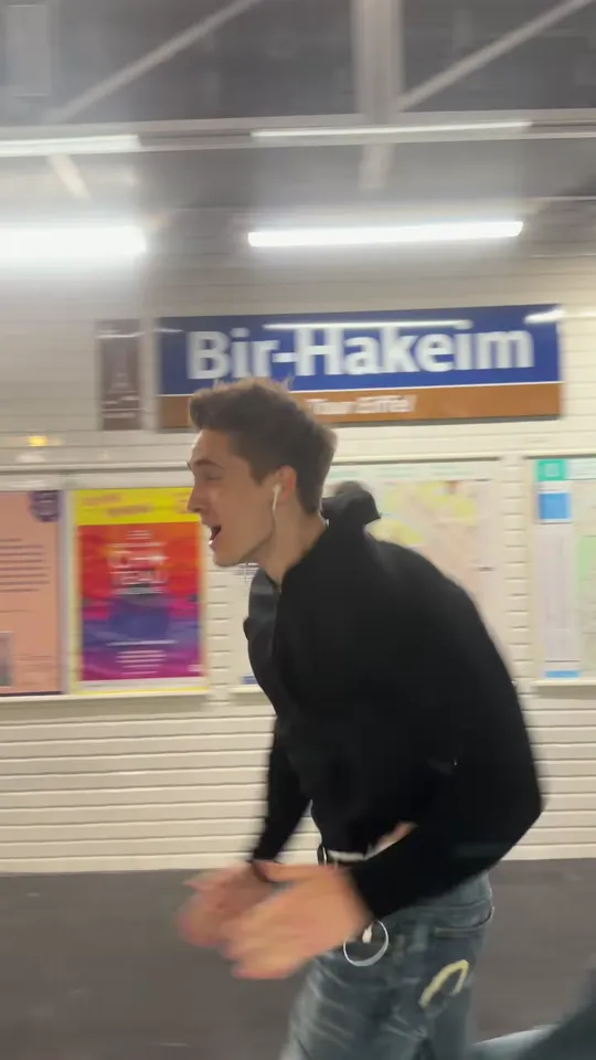 A young man sprinting along a metro platform under the Bir-Hakeim station sign, seen from the departing train
