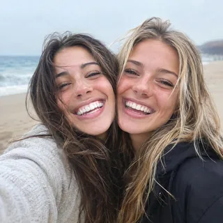 Two friends pressed cheek to cheek in a laughing selfie
