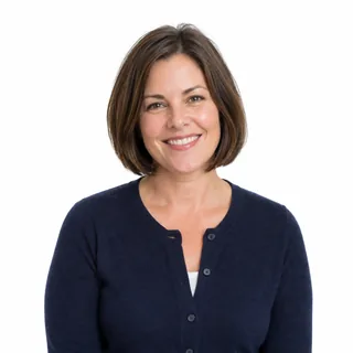 Waist-up photo of a smiling woman with a brown bob in a navy cardigan on a white background