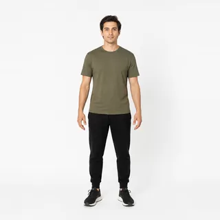 A man in an olive t-shirt on a white background, arms slightly away from his body and both hands open