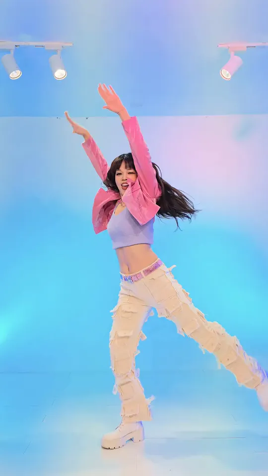 The dancer in blue light with one arm thrown up and one leg kicked out to the side
