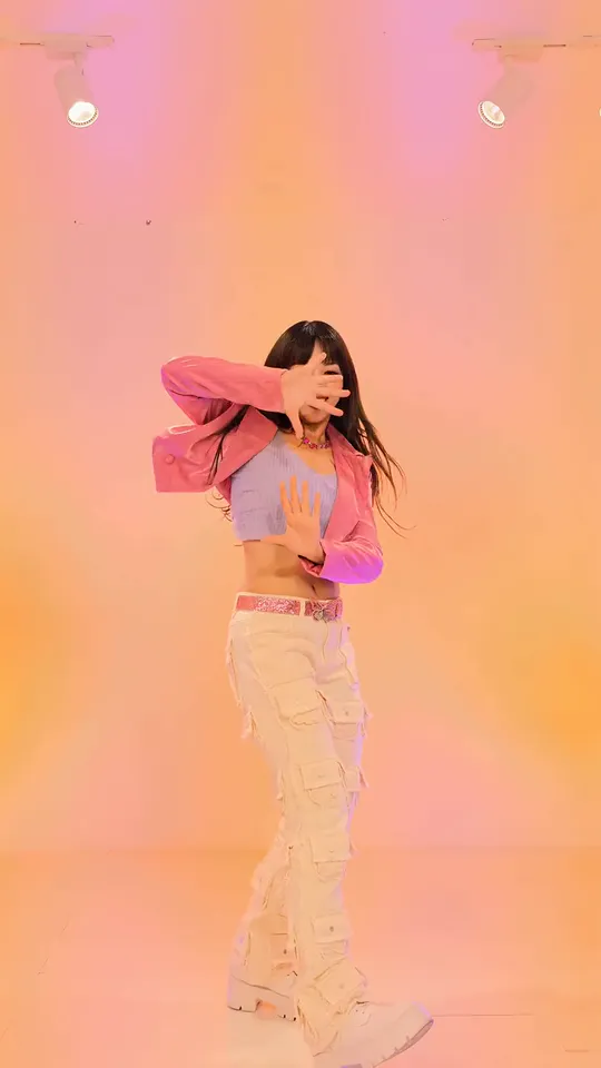 The dancer in orange light holding one hand across her eyes