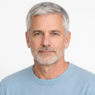 Evenly lit portrait of a grey-haired man with clearly visible eyes on a white background