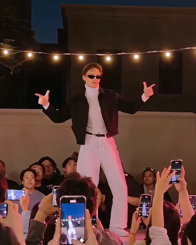 The dancer holding both arms out wide with the hands in finger guns