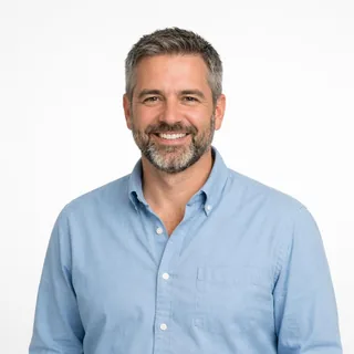 Waist-up photo of a bearded man in a light blue shirt on a white background