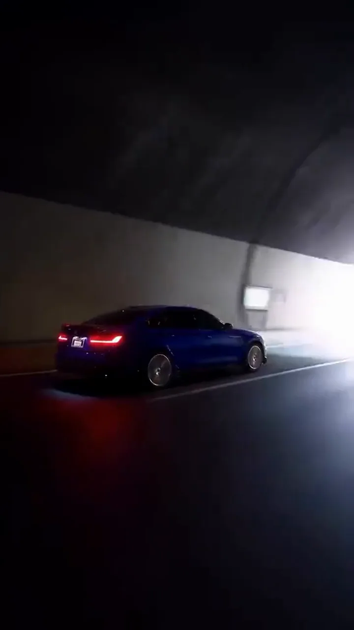 Tail lights and rear wheel of the car lit up in the dark tunnel