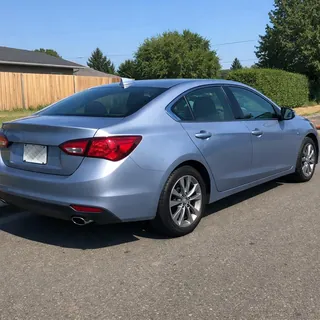 A clean sedan photographed from the rear three-quarter in bright daylight, whole body in frame