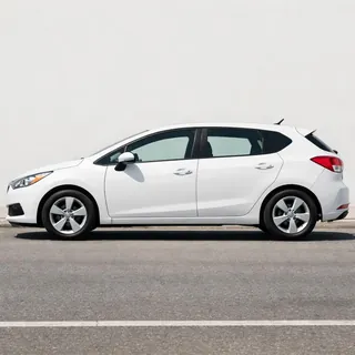 A white hatchback photographed from the side in sunlight, front and rear wheels in frame