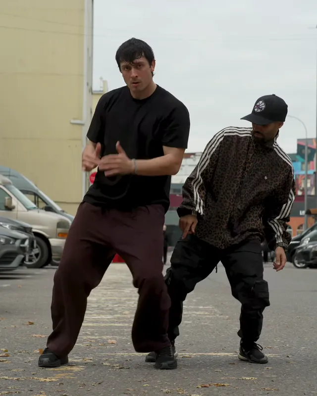 Both dancers turn one knee inward at the same moment, hands held near the chest
