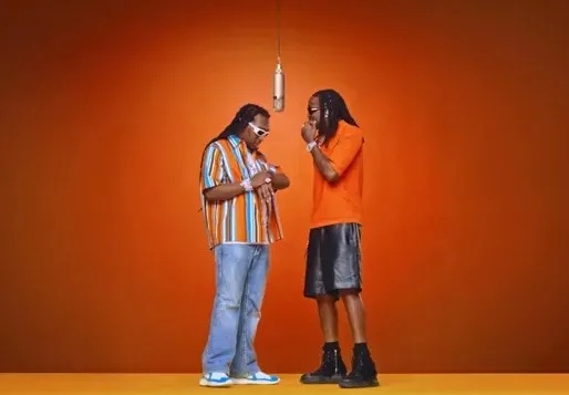 Two performers in the orange Hotel Lobby stage setup beneath a hanging microphone.